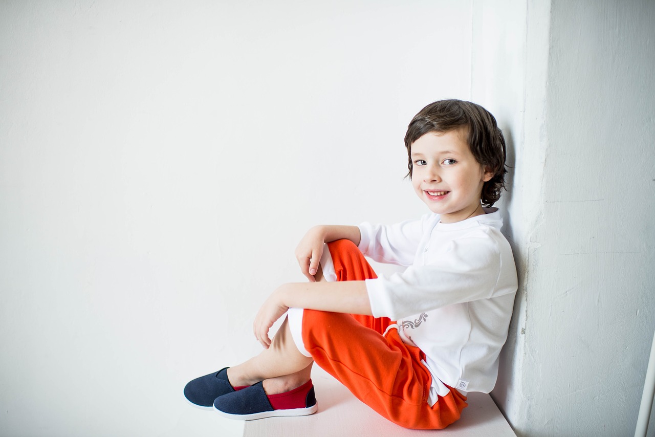 chłopiec w białej bluzce i kolorowych spodniach
